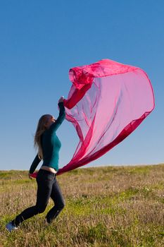 young beautiful woman jumping with tissue into the field against the sky