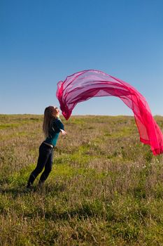 young beautiful woman jumping with tissue into the field against the sky