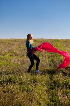 young beautiful woman jumping with tissue into the field against the sky