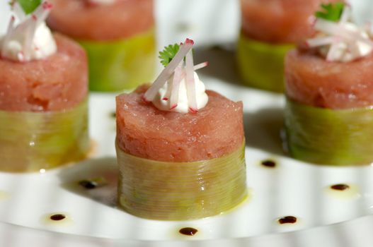 Image of raw tuna wrapped in bamboo and topped with garnish