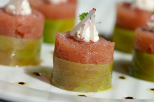 Image of raw tuna wrapped in bamboo and topped with garnish