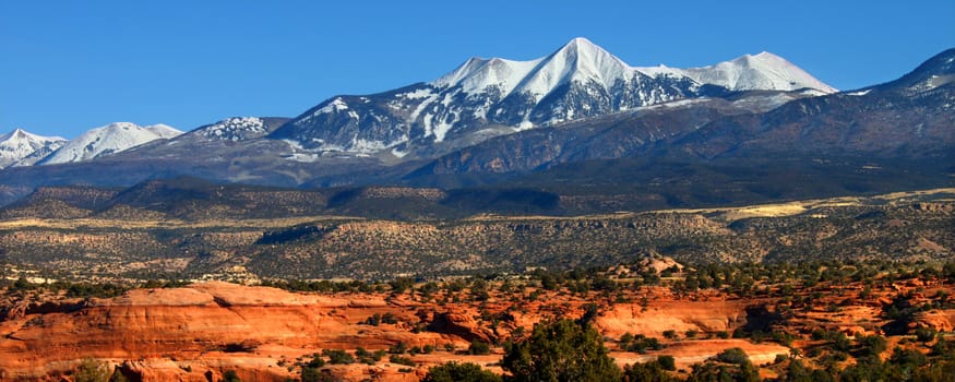 Snowcapped Mount Tukuhnikivatz of the Monti-La Sal National Forest rises above the red rock landscape in Utah.