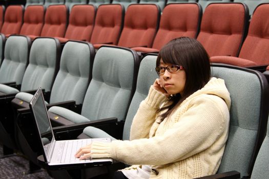 Asian student studying in lecture hall with laptop