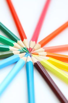 Color pencils in arrange in color wheel colors on white background