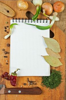 notebook to write recipes on the background of a cutting board with spices