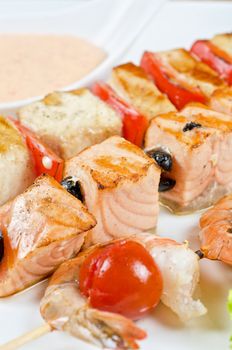 Closeup of grilled salmon and shrimps with tomatoes and peppers on bamboo sticks