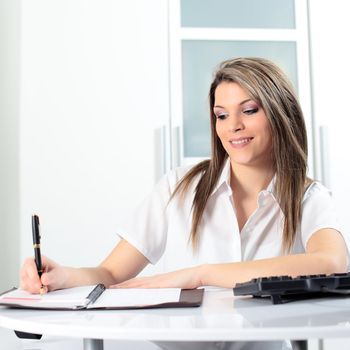 young blond secretary with pen and computer in office