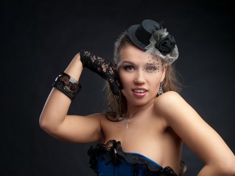 Portrait of attractive young woman in vintage style dance clothes with small top hat; studio background.