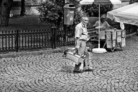 An old man carrying his shoe shine box and looking around for business