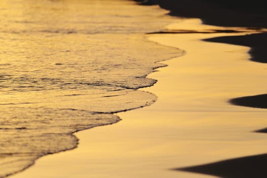 Smooth wave oh the sandy beach in the evening