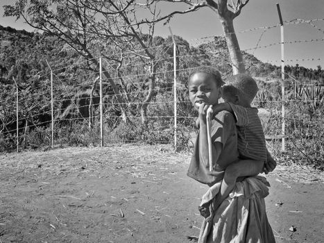 Young girl from the Konso region of Ethiopia carrying her baby brother on her back