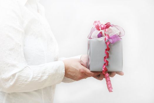 Nice gift with bow is held by women, against a white background
