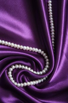White pearls on a lilac silk as background 