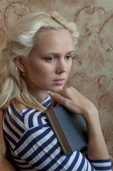 Young and beautiful girl reading a book cover in black sitting on a couch in his home