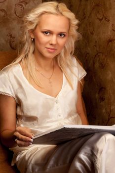 Young and beautiful girl reading a book cover in black sitting on a couch in his home