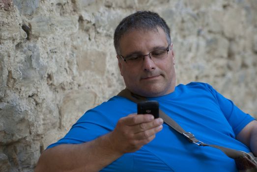 Thick nice man in blue shirt sits and stares at the phone