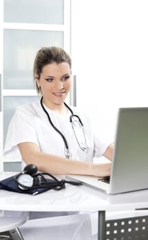 blond woman doctor in hospital with stethoscope and laptop