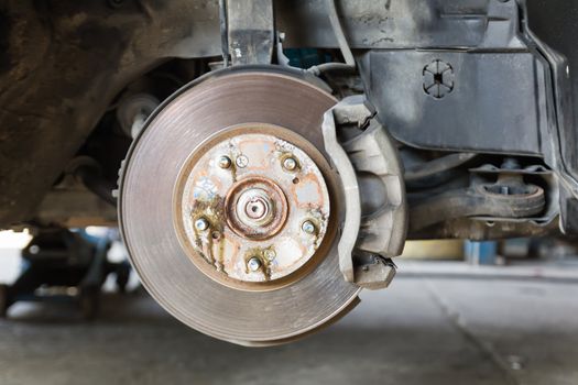Front disk brake on car in process of damaged tyre replacement. The rim is removed showing the front rotor and caliper.