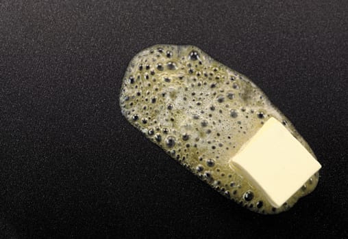 Piece of butter melting on non-stick frying pan