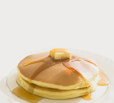 Golden pancakes with butter and warm maple syrup