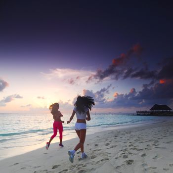 Fitness sport women running on beach at sunset