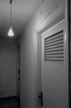 Bare light bulb and doors in underground hallway. Black and white.