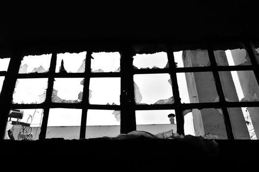 Broken window in abandoned factory. Black and white.