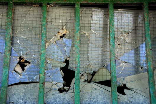 Broken thick glass behind iron bars. Abstract background texture.