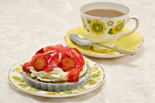 A delicious strawberry gateau and a cup of coffee on a damask cloth