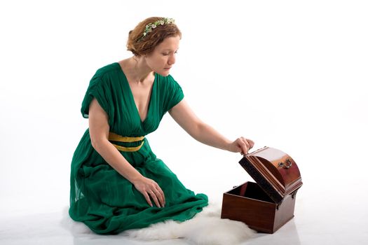 Lady in green antique dress opening box on white background
