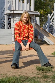 Girl in red pullover sitting on swing
