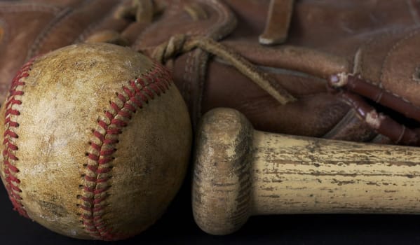 a macro picture of a baseball, glove, and bat