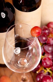 macro shot of one red grapes berry in glass. on wine bottle background