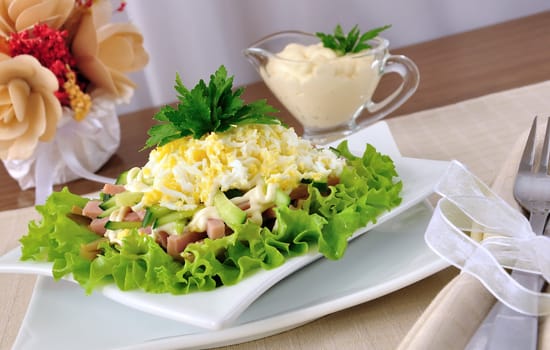 Salad with ham, cucumber, egg under the chips in the leaves of lettuce
