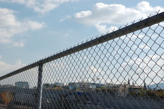 Cityscape through chain link fence. Highway barrier above the motorway.