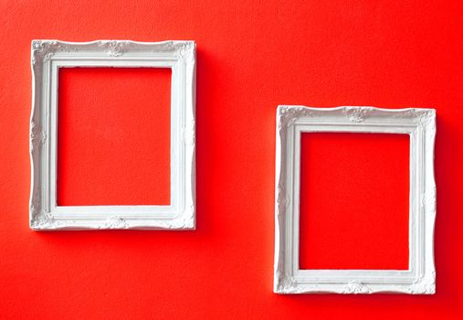 Two white vintage frames on red wall 