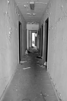 Long empty corridor and doors in abandoned building. Black and white.