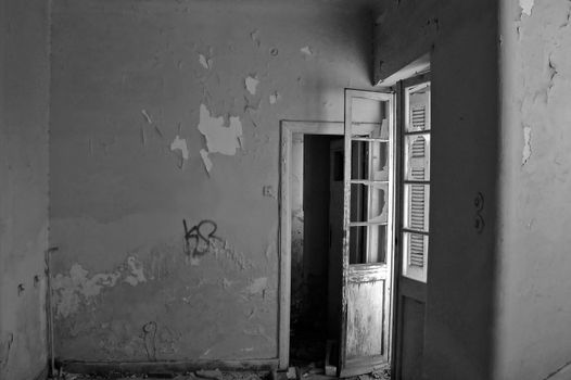 Empty room and peeling paint wall in abandoned house. Black and white.