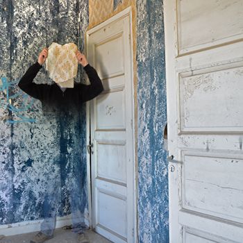Ghostly figure fading into the peeling wallpaper wall of an abandoned house.