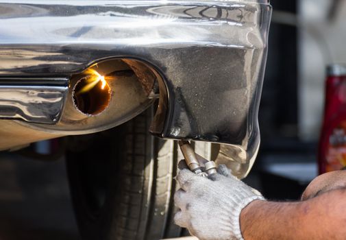 Welders were repairing  cutting exhaust pipe of a car