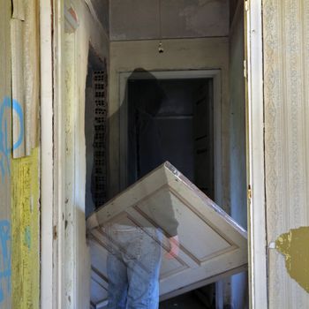 Ghost and unhinged door in the haunted hallway of an abandoned house.