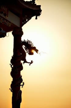 Dragon roll column statue silhouette with sunset background, Dragon eating the sun concept