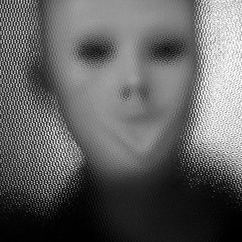 Masked distorted figure behind stained glass surface. Black and white.