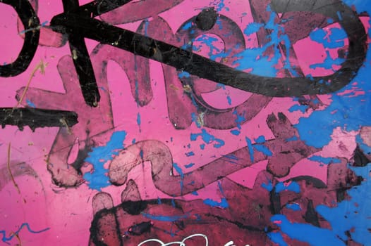 Plastic surface covered with messy graffiti and peeling paint background.