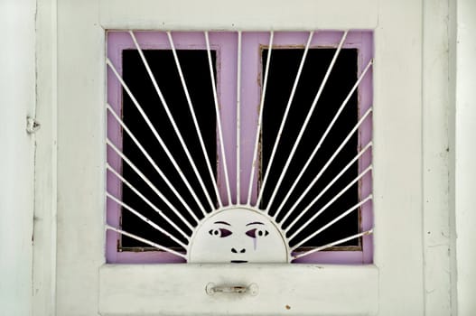 Metal sun pattern on old wooden door window. Vintage metalwork.