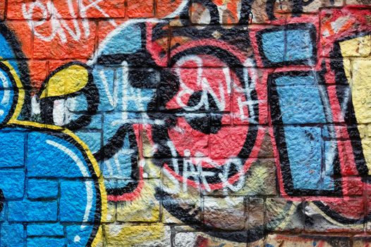 Wall with overlapping layers of messy graffiti and tags. Urban street art background.