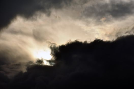 Pale light shining through black clouds. Overcast winter sky.