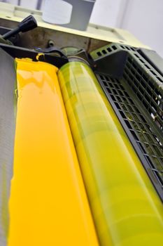 Printing press with cmyk yellow ink paint detail. Selective focus.