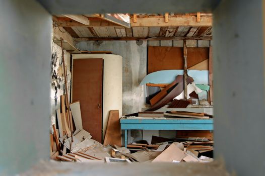View to ramshackled room with boarded up window frame in abandoned factory.