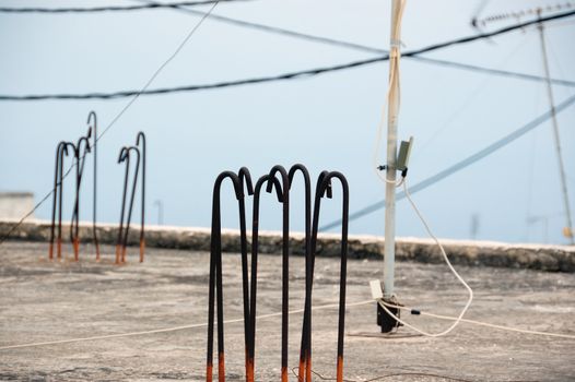 Concrete rooftop, construction bars, antenna and wires.